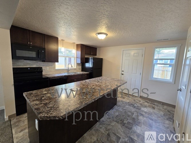 A kitchen with granite countertops and black appliances.