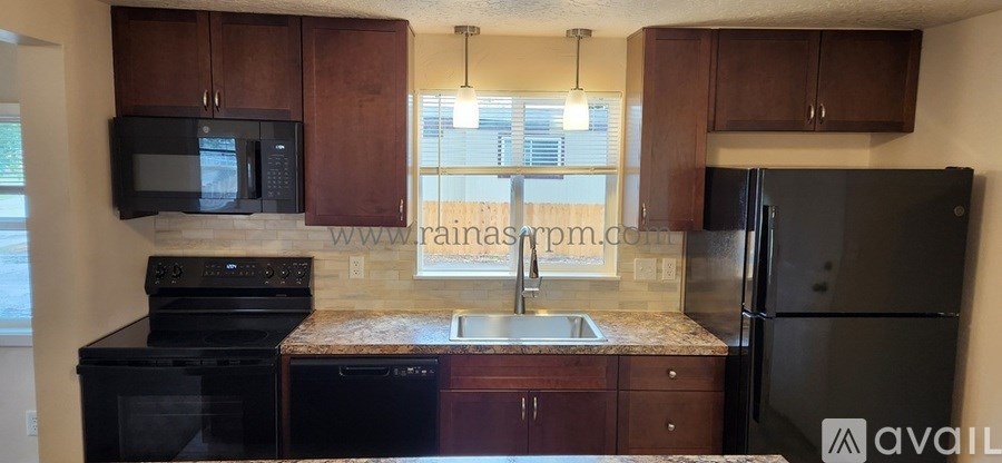 A kitchen with brown cabinets and black appliances.