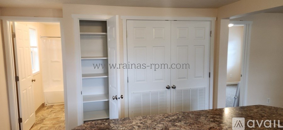 A kitchen with a granite counter top and white cabinets.