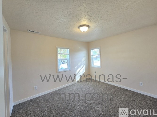A room with a carpeted floor and two windows.