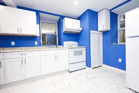 A kitchen with white cabinets and a blue wall.
