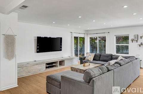 A modern living room with a grey sofa and a flat screen TV mounted on the wall.