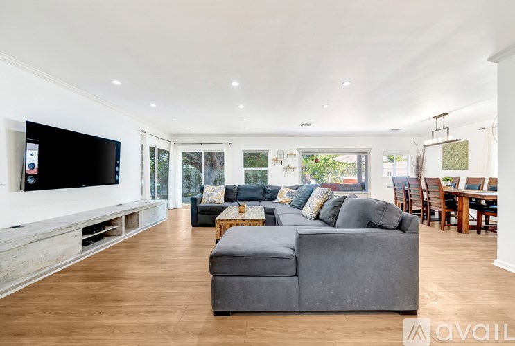 A spacious living room with a grey sofa and a television on the wall.