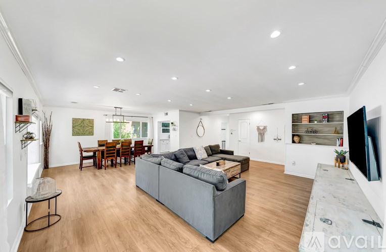 A spacious living room with a grey sofa and wooden flooring.