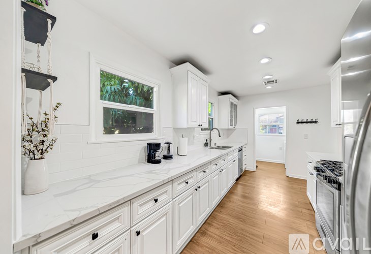 A white kitchen with wooden floors and a large island.