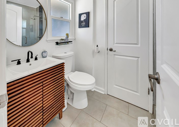 A bathroom with a toilet, sink, and mirror.