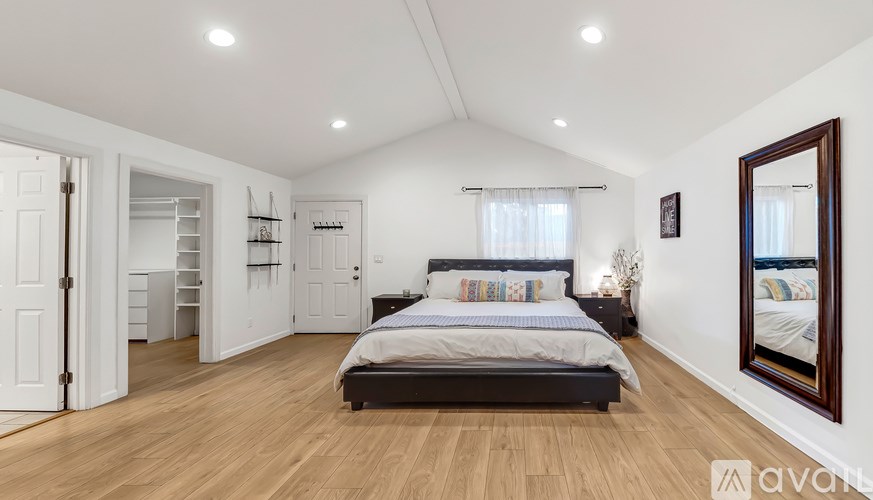 A bedroom with a large bed and a mirror on the wall.