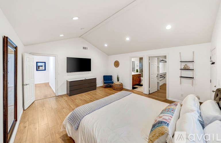 A bedroom with a large bed and a flat screen TV mounted on the wall.