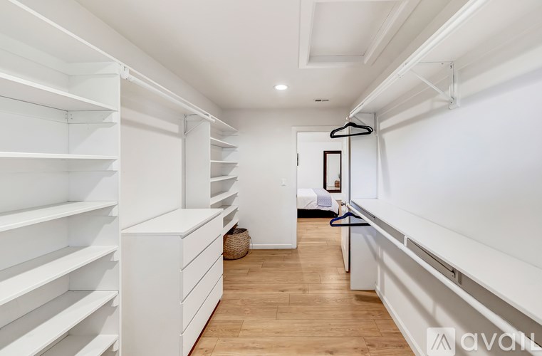 A walk-in closet with white shelves and a mirror.