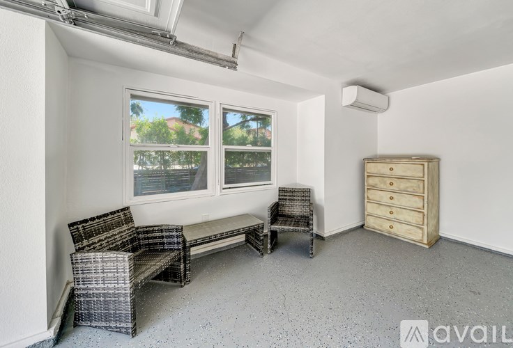 A room with a wicker sofa and a wooden chest of drawers.