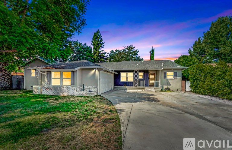 A house with a driveway and a stone wall in front.