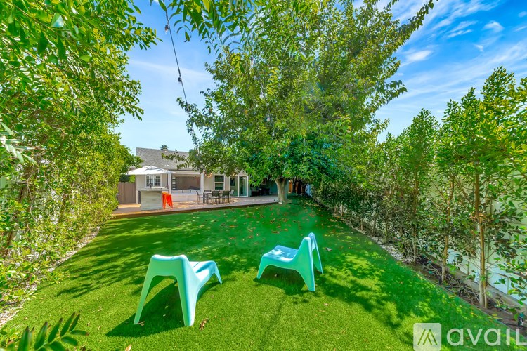 A backyard with a green lawn and two green chairs.