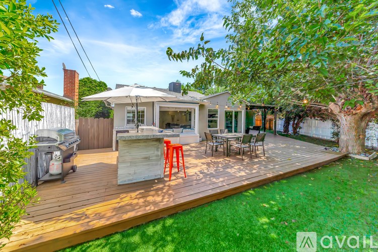 A backyard with a wooden deck and a tree.