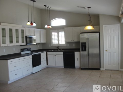 A kitchen with white cabinets and black countertops.