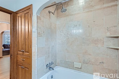 A bathroom with a tiled shower area and a wooden door.
