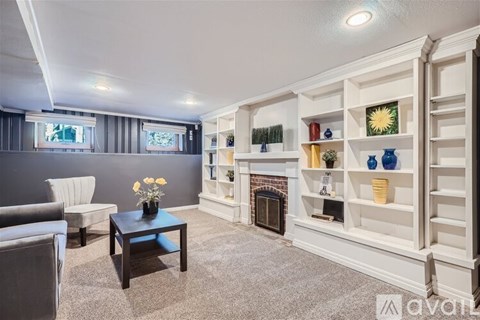 A living room with a grey couch, a coffee table, and a fireplace with a mantelpiece above it.