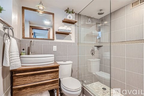 A bathroom with a toilet, sink, and mirror.