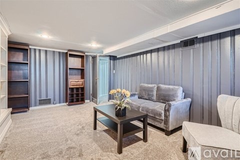 A living room with a grey couch, a coffee table, and a white chair.