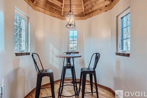 A dining area with a table, two chairs and a hanging light fixture.
