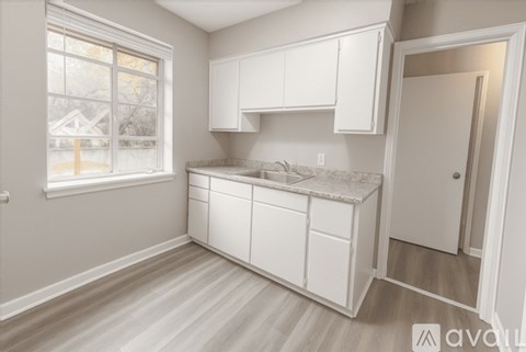 A kitchen with white cabinets and a window.