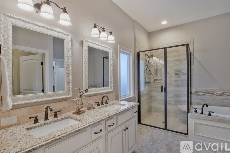 A bathroom with a vanity, two sinks, and a walk-in shower.