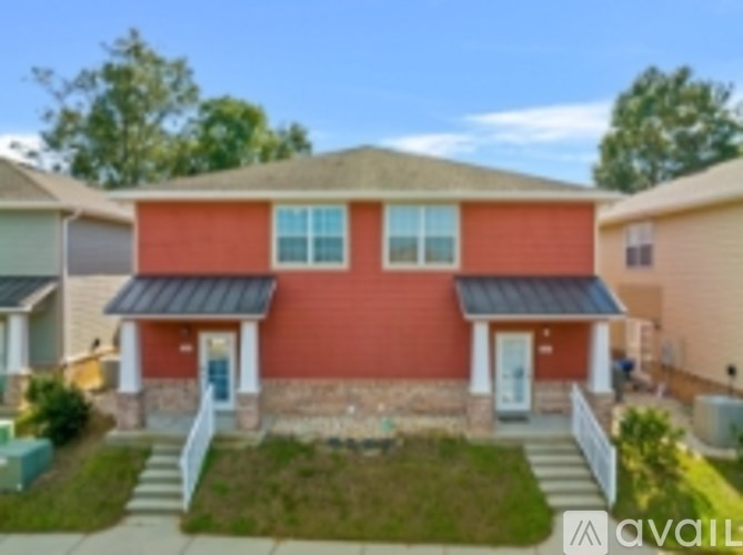 A red house with a black roof and a white fence in front.