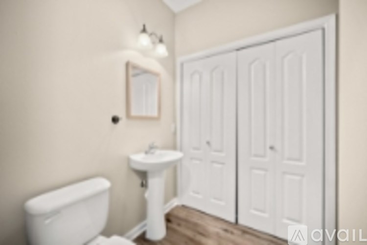 A white toilet sits next to a white sink in a small bathroom.