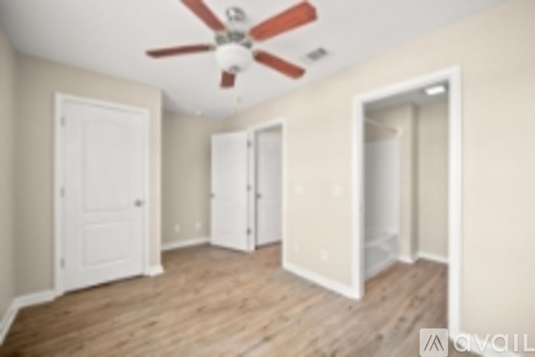 A room with a ceiling fan and three doors.
