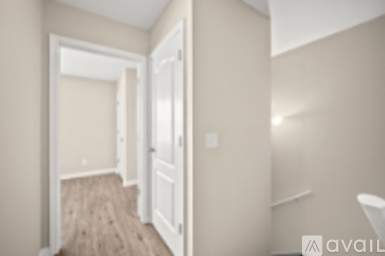 A hallway with a door on the left and a staircase on the right.