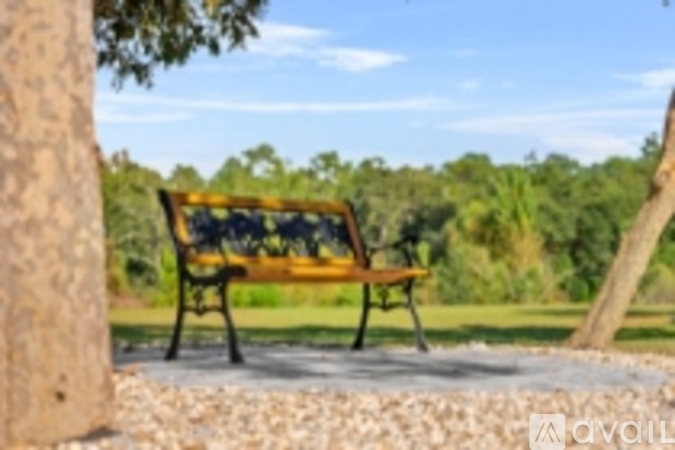 A bench with a yellow seat and black backrest sits on a gravel area.