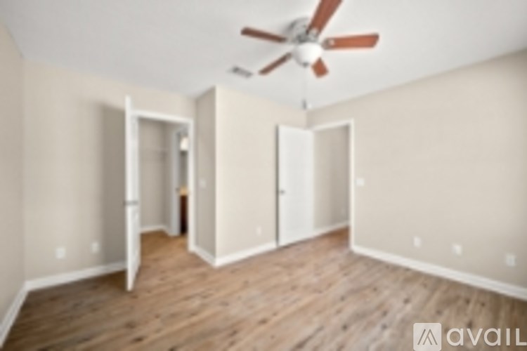 A room with a ceiling fan and wooden floors.