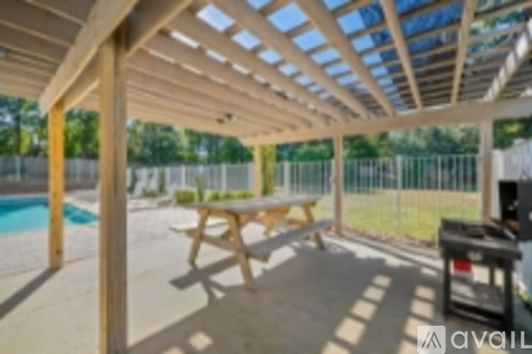 A wooden table is on a patio with a pool in the background.