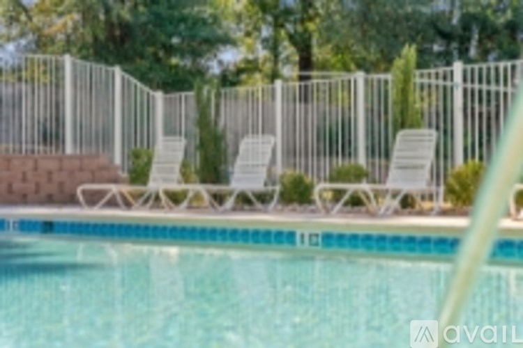 A pool with a white fence and chairs around it.