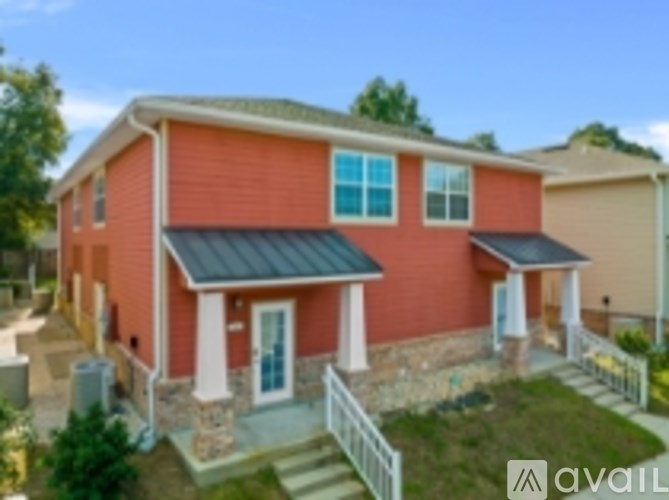 A red house with a black roof and a white fence in front.