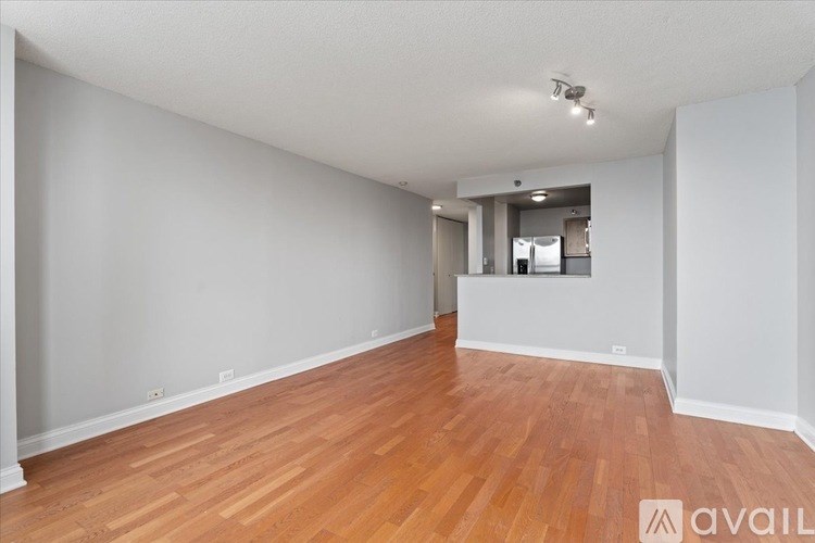 A room with wooden floors and white walls is available for rent.
