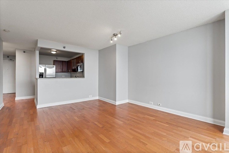 A spacious room with wooden flooring and white walls.