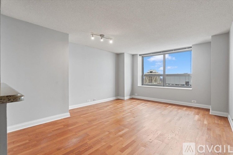 A room with wooden flooring and a window overlooking a building.