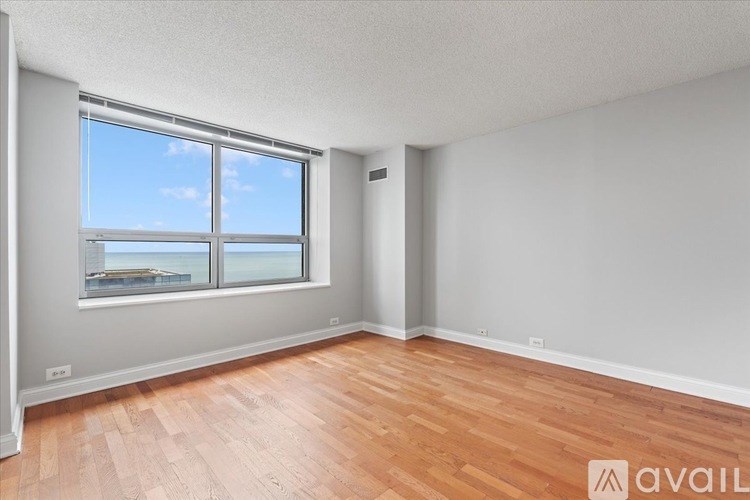 A room with wooden floors and a large window overlooking a body of water.
