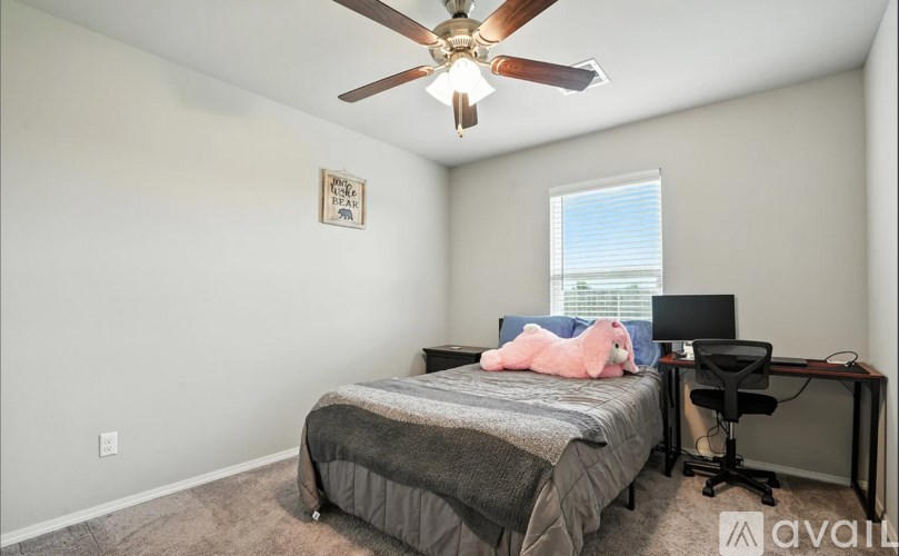 A bedroom with a bed, desk, and ceiling fan.