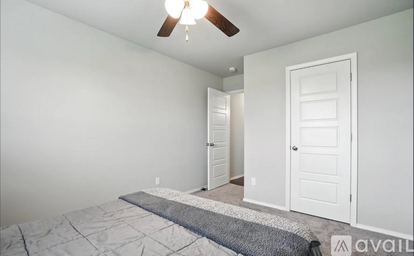 A bedroom with a bed, a ceiling fan, and two doors.