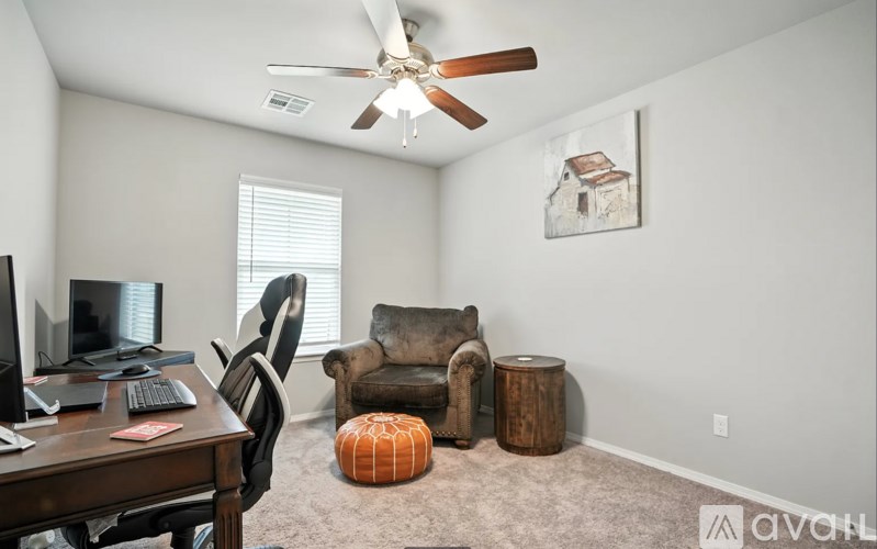 A room with a ceiling fan, a desk with a computer, and a chair.