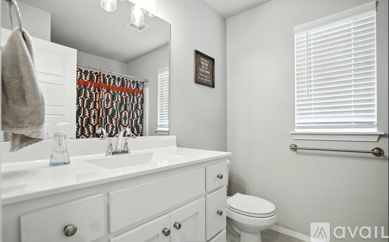 A bathroom with a toilet, sink, and a window with blinds.