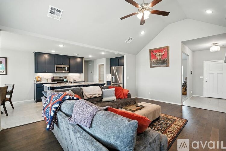 A living room with a grey couch and a ceiling fan.