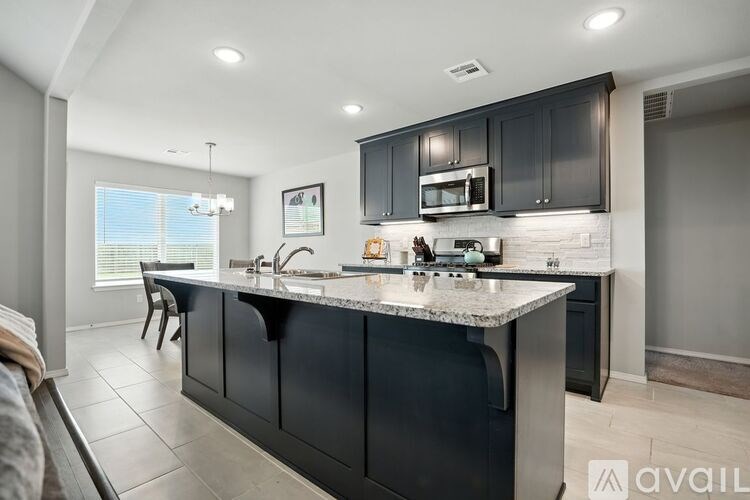 A modern kitchen with black cabinets and a marble countertop.