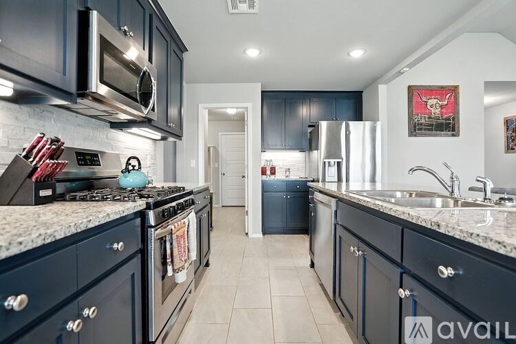 A kitchen with dark blue cabinets and a white stove top oven.