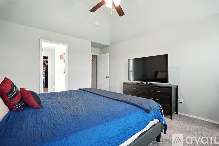A bedroom with a blue bedspread and a television on a dresser.