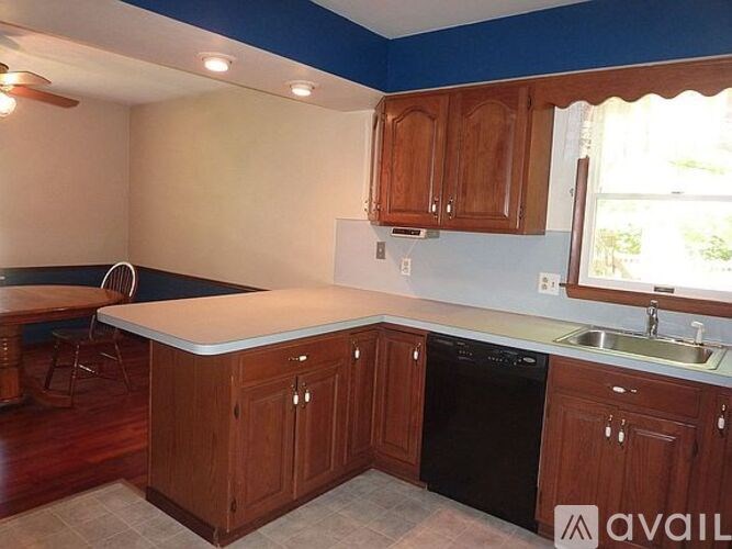 A kitchen with wooden cabinets and a black dishwasher.