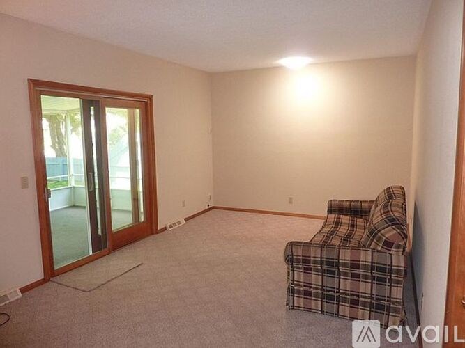 A room with a plaid chair and a sliding glass door.
