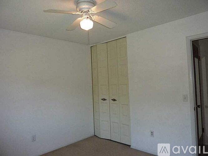 A room with a ceiling fan and a white door.