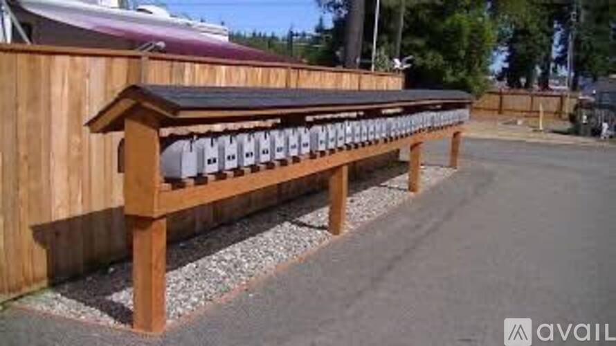 A wooden bench with a black roof is situated on a gravel area.